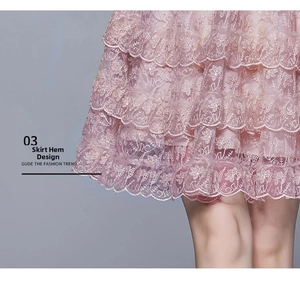Detailed view of layered lace hem with intricate floral embroidery on a pink dress