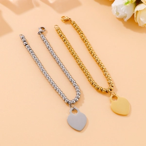 Detail view of 18k gold and silver beaded bracelets featuring polished heart pendants