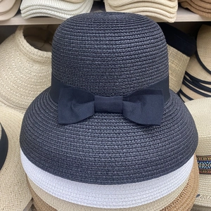 Detail of a black woven sun hat featuring a delicate matching ribbon bow decoration