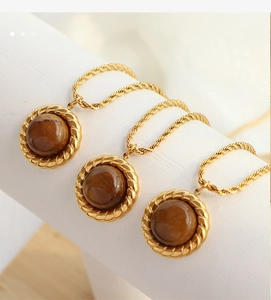 Detailed view of three gold vintage necklaces with round tiger eye pendants on white stands