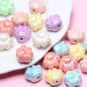 Pastel cat claw acrylic beads for DIY bracelets scattered on a white embossed plate