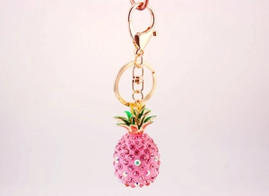 Close-up of pink rhinestone pineapple keychain with green enamel leaves and gold plating