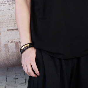 Macro shot of multilayered black braided leather bracelet with matte gold magnetic buckle