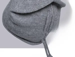 Detail of dark grey knit beanie showing dense stitch texture and woven drawstrings