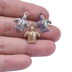Close-up of turtle pendants in gold, silver and rainbow colors on fingertips