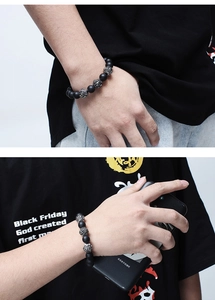 Detail showing a punk beaded bracelet with matte black agate and silver skull charms on a wrist