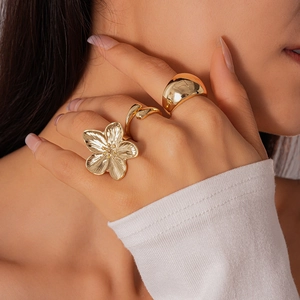 Detailed view of a gold flower ring set with textured petals and a wide polished band