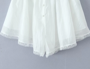 Detail shot of white fabric with delicate lace trim and matching button decorative design