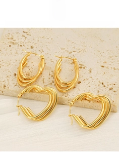 Detail of layered gold titanium steel earrings in heart and oval shapes on stone