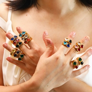 Close-up of multicolor heart-shaped gemstone rings in 18k gold-plated finish on a model