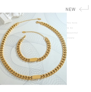 Détail d'un ensemble collier et bracelet maille gourmette dorée avec plaques ID lisses
