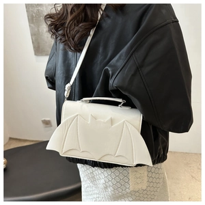 Detailed view of creative white bat-shaped shoulder bag on model with black jacket