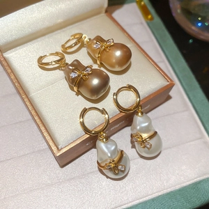 Détail de boucles d'oreilles perles baroques plaquées or 18 carats et nœud zircon