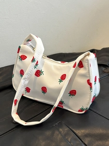 Close-up of white nylon handbag with red strawberry pattern and top zipper detail