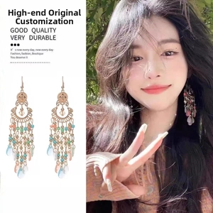 Detail of bohemian drop feather earrings with colorful beads and gold hollow design