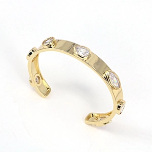 Detailed macro view of gold-plated cuff bracelet featuring inlaid white zircon stones
