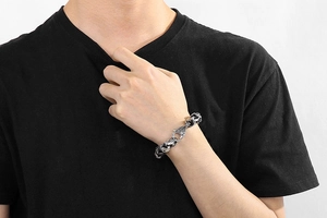 Détail d'un bracelet punk tête de mort en acier inoxydable avec gravures gothiques au poignet