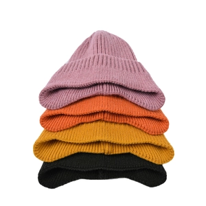 Berretti invernali in maglia a costine in rosa, arancio, giallo e nero impilati con cura
