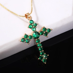 Elegant gold necklace with emerald green zircon cross pendant on a chic reflective surface