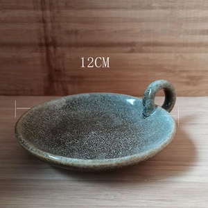 Detailed view of a 12cm speckled ceramic candle plate with handle on wooden texture