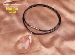 Close-up of black waxed cord necklace with stainless steel clasp and teardrop pendant
