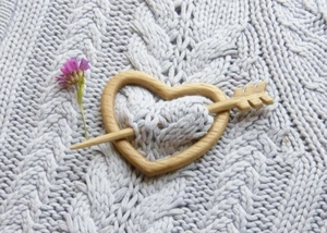 Detail of a heart-shaped wooden brooch pin with arrow fastener on a knitted sweater