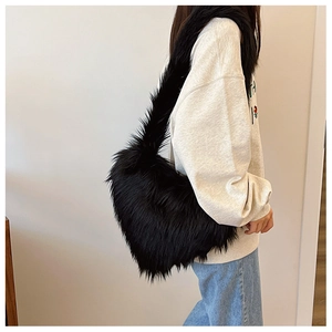 Faux fox fur heart-shaped crossbody bag in black worn by a model in casual style
