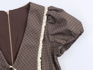 Detail of brown plaid dress featuring crochet lace trim and delicate puff sleeve seams