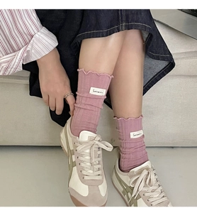 Detailed close-up of pink frilly crew socks with a Surinanin fabric label on the side