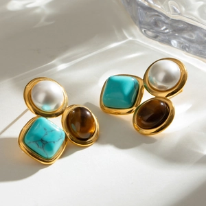 Macro shot of vintage gold stud earrings featuring pearl and turquoise stones