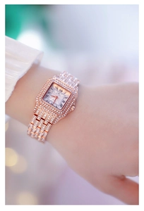 Close-up of rose gold square watch with crystal-encrusted bezel and Roman numeral dial