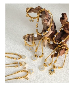 Detail of 18K gold plated bracelet featuring star, heart, and Hamsa hand charms