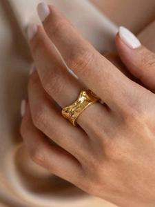 Macro shot of irregular textured gold stainless steel ring on model finger