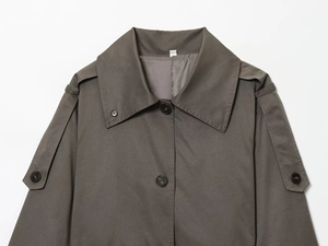 Detailed view of large lapel collar and shoulder epaulettes on a dark grey trench coat