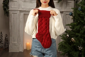 Close-up of red cable knit Christmas stocking with warm holiday fireplace background