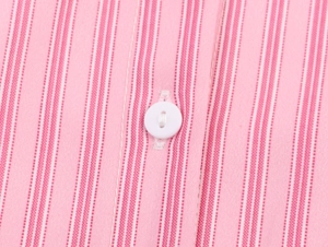 Dettaglio macro di tessuto a righe verticali rosa e bianche con bottone bianco