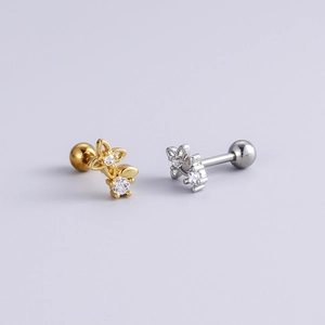 Close-up of gold and silver flower stud earrings with zircon stones and ball screw backs