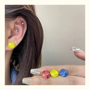 Macro shot of colorful square-cut crystal stud earrings in blue, pink, and yellow