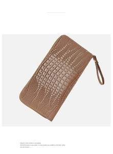 Detalle de cartera larga marrón con textura de cocodrilo, cremallera y correa de mano