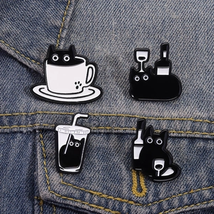 Set of four cute cartoon black cat enamel pins on denim fabric showing coffee and tea themes