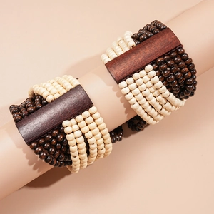 Détail de bracelets multicouches en perles de bois aux tons contrastés marron et crème