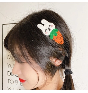 Dettaglio di un fermaglio per capelli lavorato a maglia con coniglio e carota
