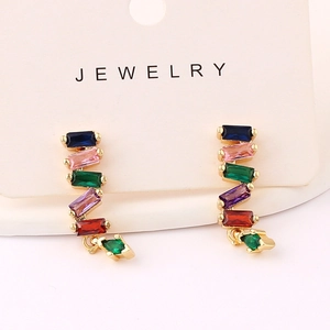 Detail of gold earrings with rectangular multicolored stones and green crystals