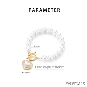 Detailed view of pearl bead bracelet with gold OT clasp and diamond heart pendant