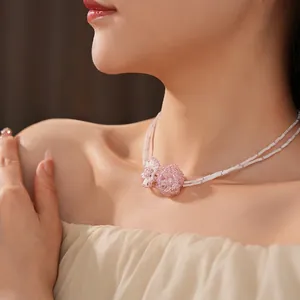 Elegant double-layered beaded necklace with pink flower pendants on a bamboo-style chain