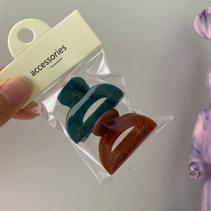 Pair of jelly mini hair claws in dark green and amber brown inside clear packaging