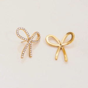 Close-up of golden bow earrings featuring one diamond-pave and one smooth metal finish