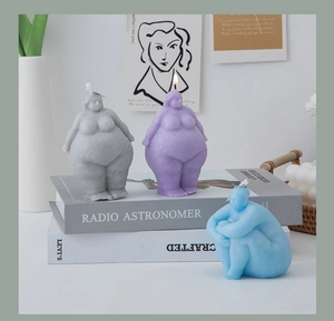 Close-up of handmade human body art candles in blue, purple, and grey on a rustic setup