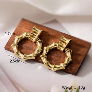 Detail showing 2.7x2.5cm bamboo-textured 18K gold earrings on wood with 10g weight display
