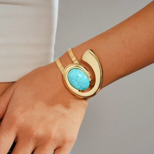 Detail of wide gold cuff bracelet featuring a large turquoise textured resin oval stone